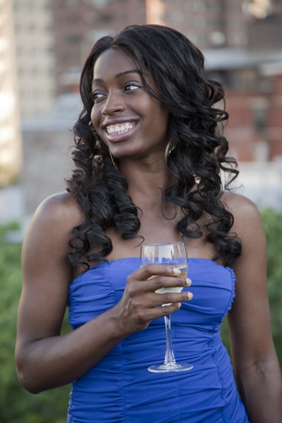 Glamorous African American woman drinking wine outdoors