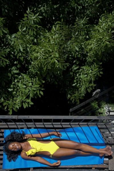 Black woman sunbathing on fire escape