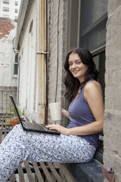 Woman using laptop on fire escape