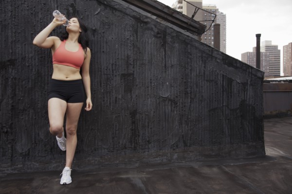 Woman in sportswear drinking water on rooftop