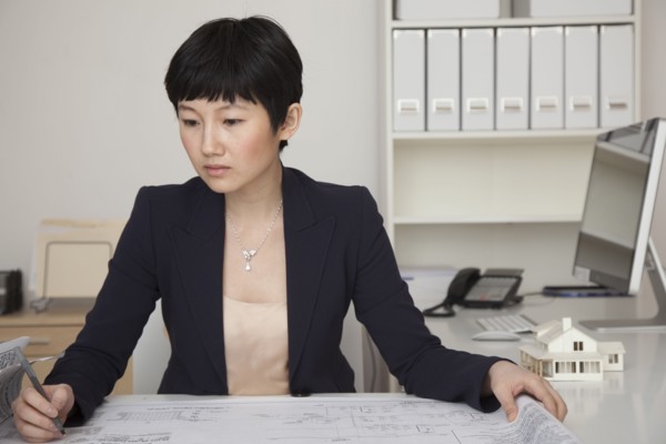 Businesswoman examining blueprints in office