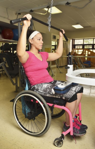 Paraplegic woman in wheelchair working out in physical therapy