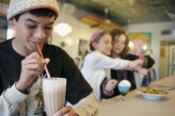 Mixed race boy drinking milkshake in cafe
