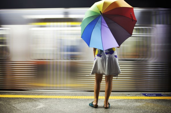 Mixed race woman with umbrella on train platform
