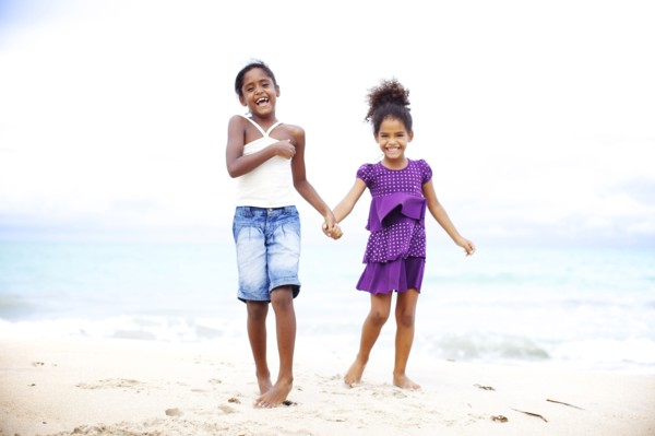 Mixed race sisters holding hands on beach