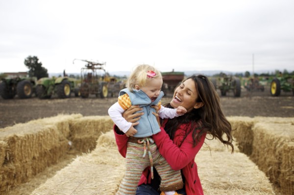 Mother and daughter enjoying playing on hay bales