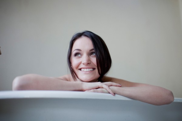 Caucasian woman leaning on side of bathtub