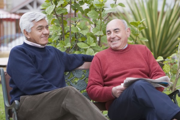 Senior Hispanic friends sitting on park bench