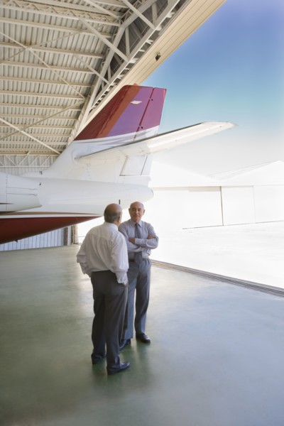 Hispanic businessmen standing in airplane hangar