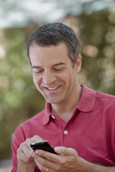 Hispanic man text messaging on cell phone