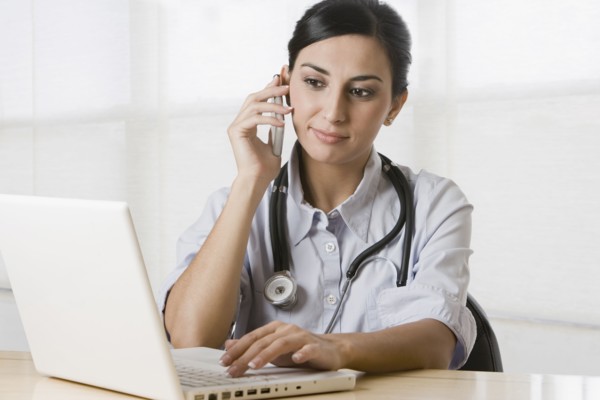 Turkish doctor talking on cell phone and using laptop