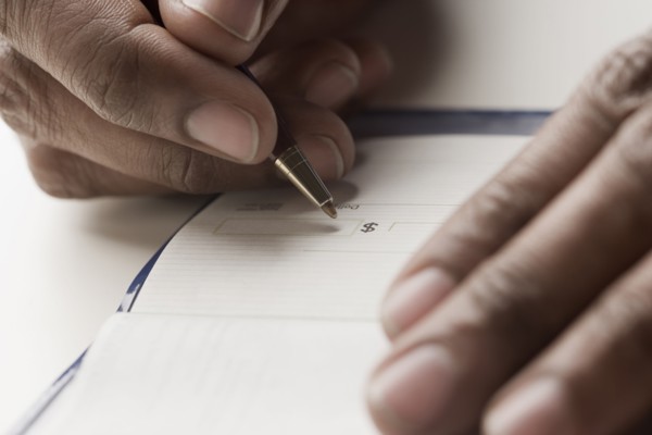 Mixed race man writing a check