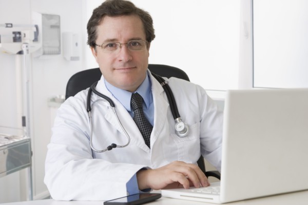Caucasian doctor sitting at desk with laptop