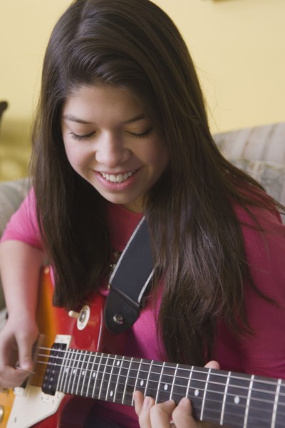 Hispanic girl playing guitar on sofa