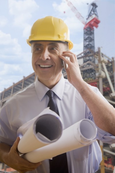 Hispanic architect talking on cell phone at construction site