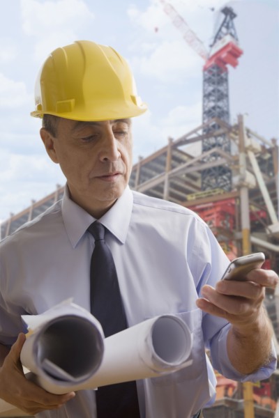 Hispanic architect using cell phone at construction site