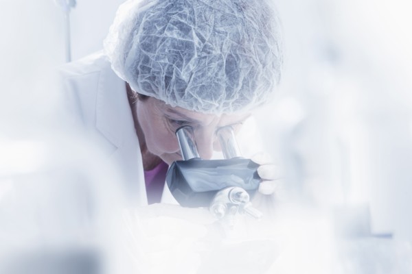 Hispanic scientist using microscope in lab