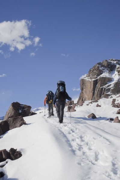 Hispanic hikers walking on snowy mountain