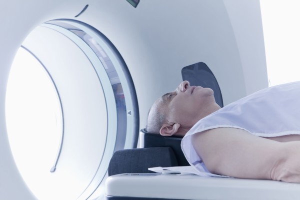Older Hispanic man laying in MRI scanner
