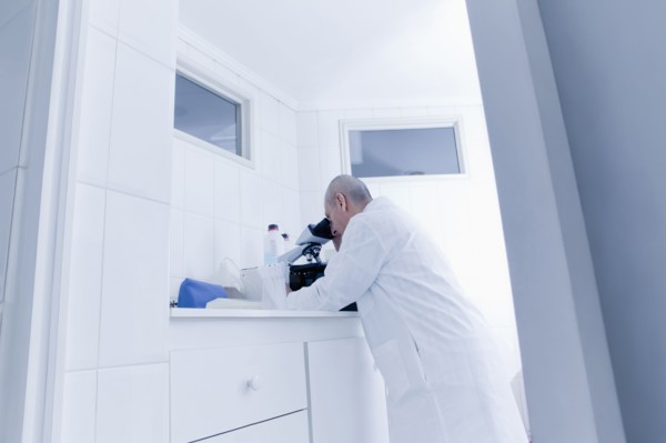 Hispanic scientist using microscope in lab