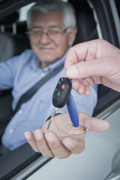 Hispanic car salesman handing keys to customer