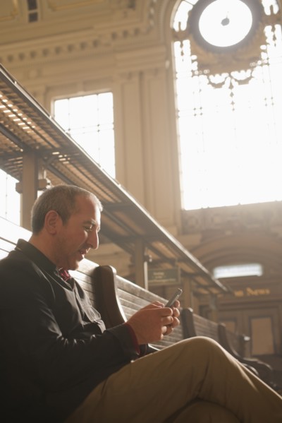 Hispanic man reading newspaper in train station