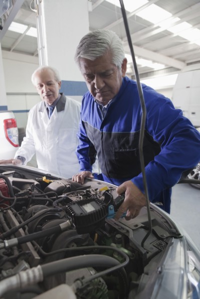 Older Hispanic mechanics repairing car in garage