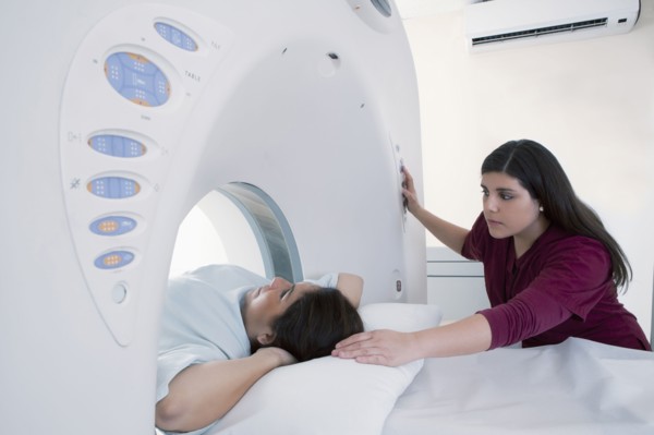 Hispanic nurse examining patient in MRI machine