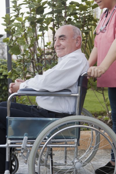 Hispanic nurse pushing patient in wheelchair