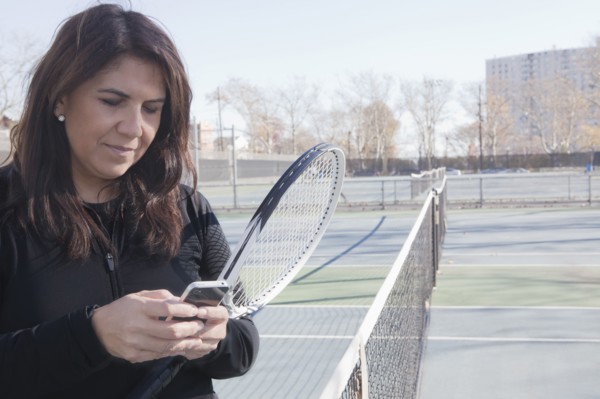 Hispanic woman using cell phone on tennis court