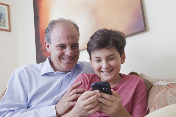 Hispanic father and son texting on cell phone