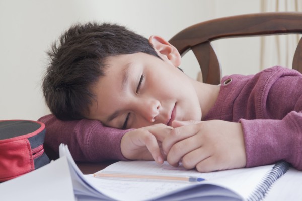 Hispanic boy sleeping on homework at table