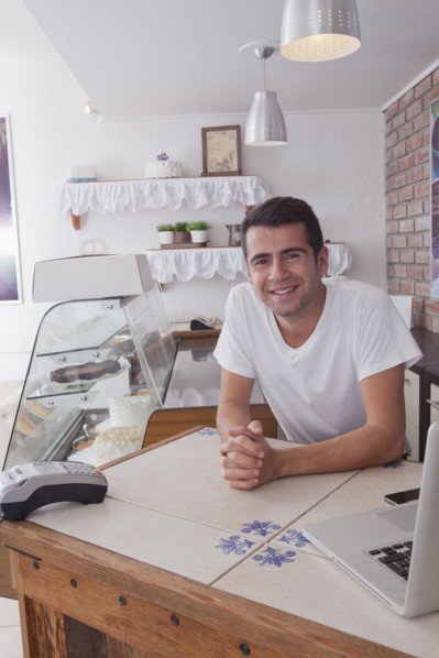 Smiling Hispanic baker leaning on counter