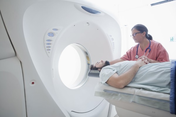 Hispanic nurse comforting patient at scanner