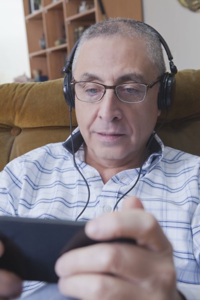 Curious Hispanic man listening to cell phone with headphones