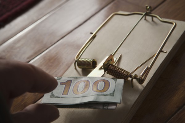 Hand of Hispanic man placing money in mousetrap