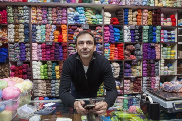 Mixed Race man texting on cell phone at yarn store