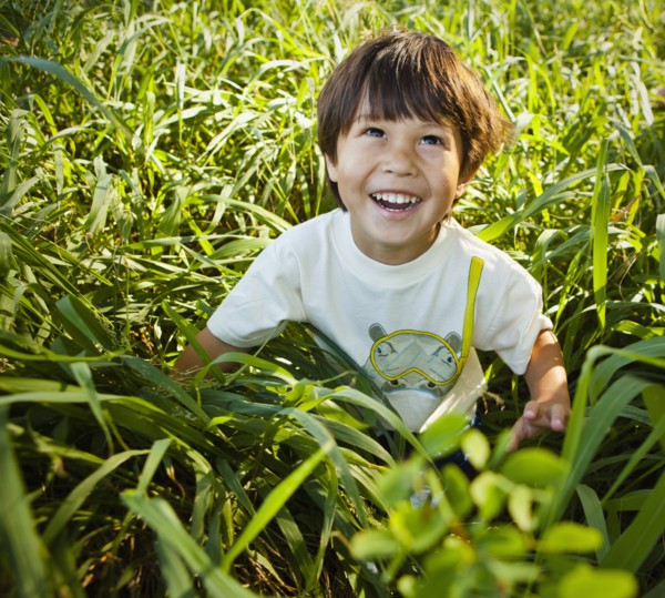 Grinning mixed race boy sitting in long grass