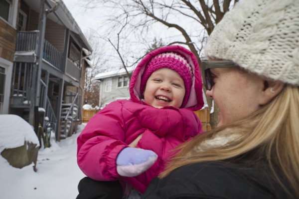 Mother holding grinning girl in coat