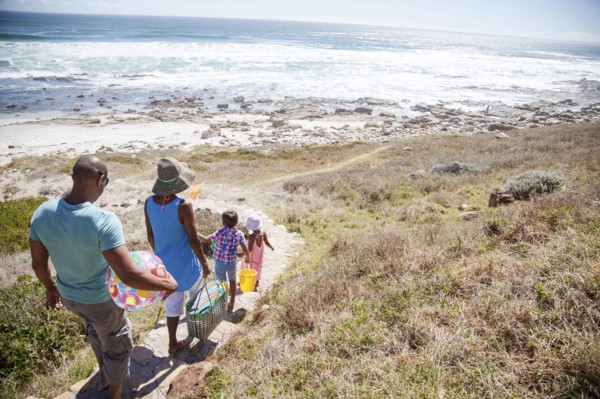 Mixed race family walking on path to beach
