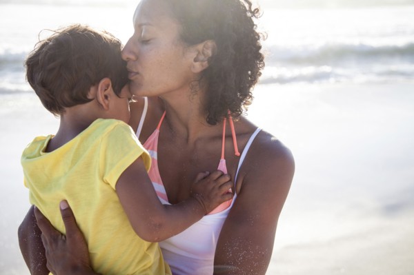 Mixed race mother kissing daughter on beach