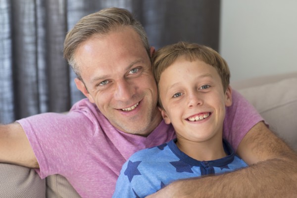 Caucasian father and son hugging on sofa
