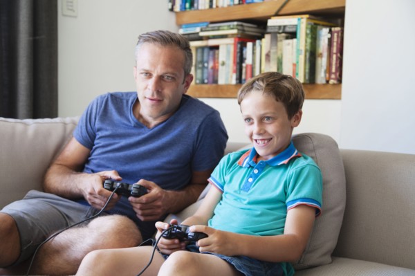 Caucasian father and son playing video games on sofa