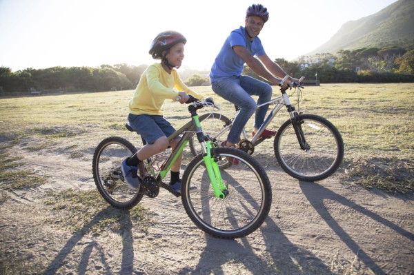 Caucasian father and son riding bicycles on dirt path
