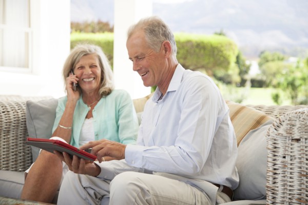 Caucasian couple using cell phone and digital tablet on sofa