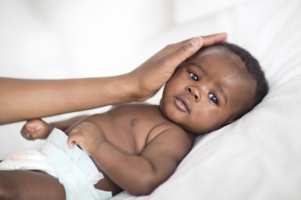 Close up of Black mother patting baby on bed