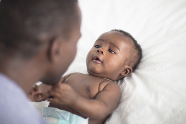 Close up of Black father playing with baby on bed