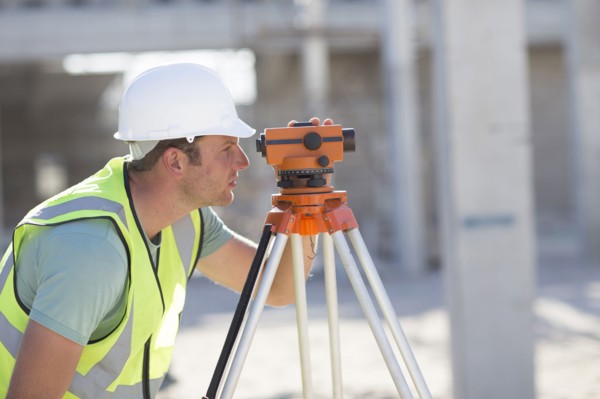 Caucasian surveyor examining construction site