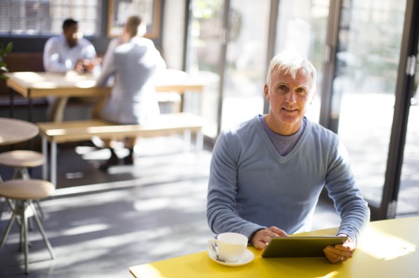 Older man using digital tablet in cafe