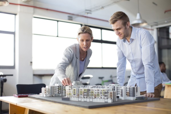 Caucasian architects examining architectural model in office